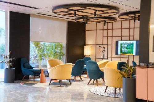 a waiting room with chairs and a table and a tv at Ramada Encore by Wyndham Chandigarh Zirakpur in Zirakpur