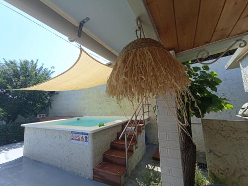 a hot tub with a straw umbrella on a patio at Wooden Summer House in Mantoúkion