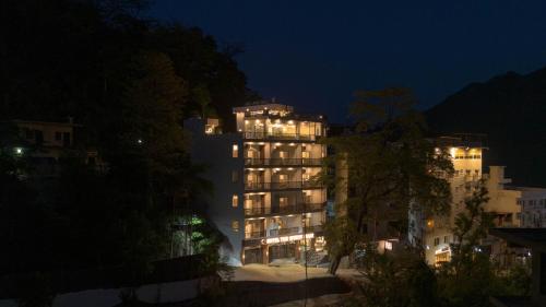 a tall building with lights on at night at Perfectstayz Premium Mystic falls with Rooftop Pool & Cafe in Narendranagar