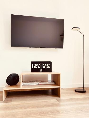 a living room with a tv and a clock on a table at Le Cocon des Tilleuls - Duplex 2 Ch - Parking inclus au pied du logement ! in Liège