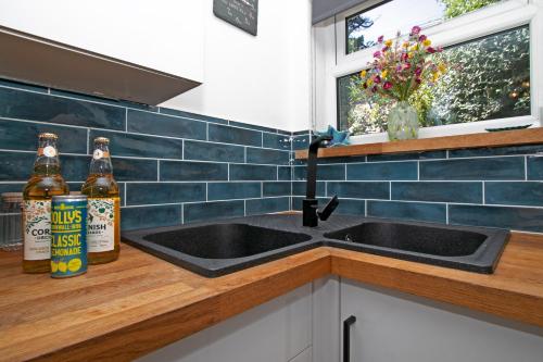 a kitchen with two bottles of beer next to a sink at 7 Porth Valley Cottage's in Newquay