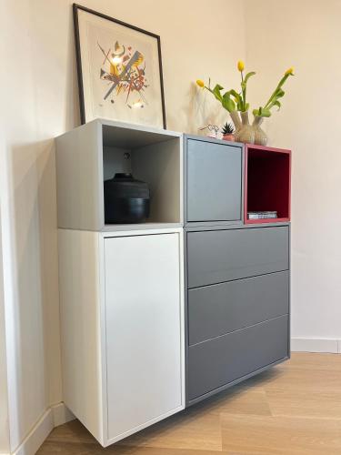 a white cabinet with four drawers and a clock at Le Cocon des Tilleuls - Duplex 2 Ch - Parking inclus au pied du logement ! in Liège