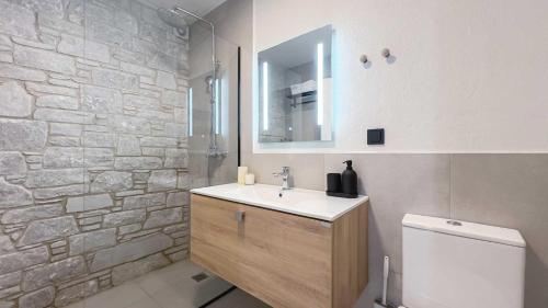a bathroom with a sink and a stone wall at Damari Luxury Retreat Villas Skiathos in Skiathos Town