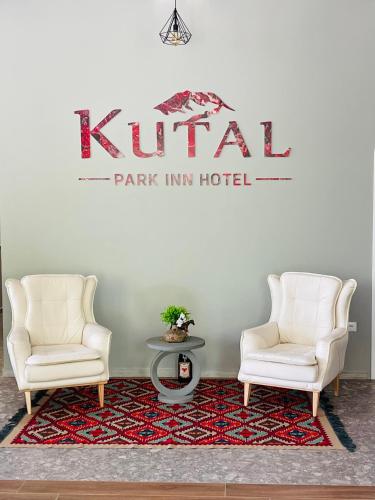 two chairs and a table with a sign on the wall at Kutal Park Inn Hotel in Përmet