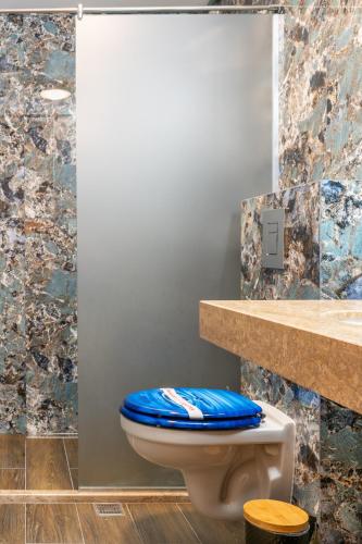a bathroom with a toilet with a blue seat at Royal Calisto Hotel in Sozopol