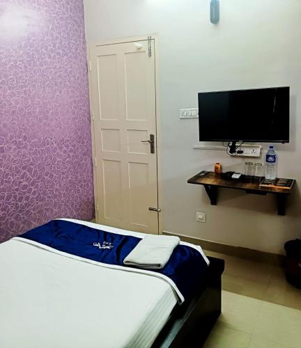 a room with a bed and a tv and a door at Swapna Home Suites in Nedumbassery