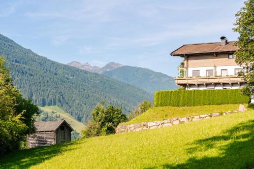 a house on a hill with mountains in the background at Pension Schlossberg in Mittersill