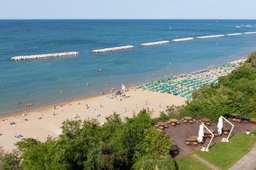 a beach with a lot of people and the ocean at Hotel Sans Souci in Gabicce Mare