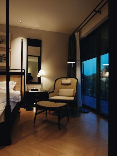 a bedroom with a bed and a chair and a table at Argo Pattaya Resort and Villas in Ban Huai Yai