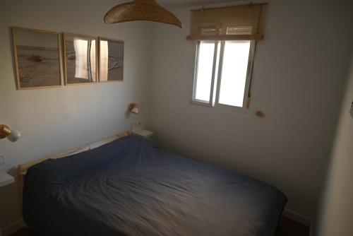 a bedroom with a blue bed and two windows at Casa en casco antiguo de Barbate in Barbate