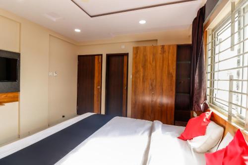 a bedroom with a large bed and a window at Capital O N R Residency in Bengaluru