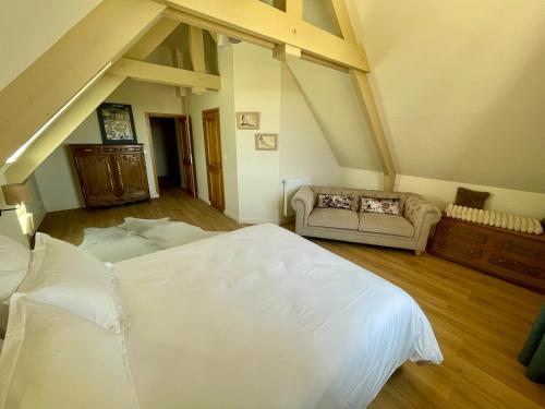 une chambre avec un grand lit blanc et un canapé dans l'établissement Gîte de La Baumée, à Hiesville