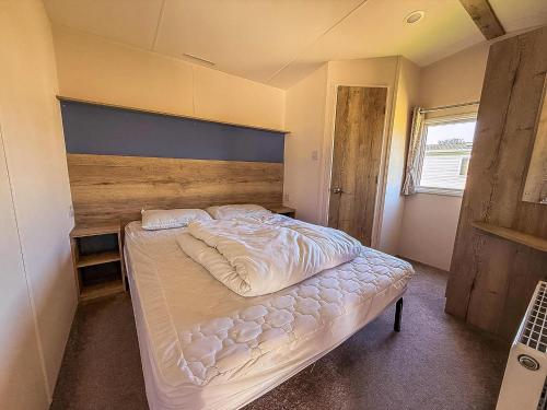 a bedroom with a large bed with a wooden headboard at Lovely 6 Berth Caravan Close To The Beach In Suffolk Ref 68030Bs in Lowestoft