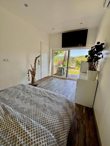 a bedroom with a bed and a flat screen tv at Petit Havre de Paix avec Jacuzzi Luxe & Jardin Privatif Zen in Cavalaire-sur-Mer
