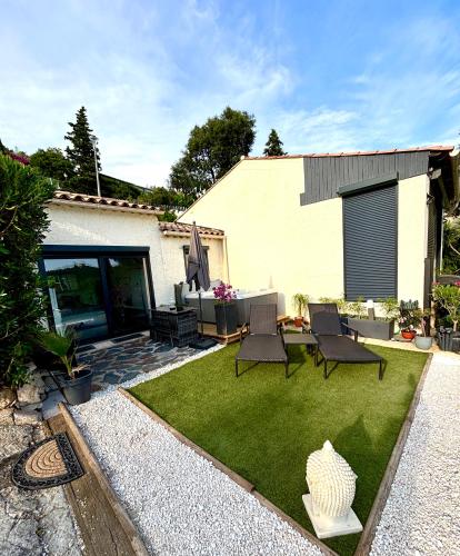 a backyard with a lawn with chairs and a table at Petit Havre de Paix avec Jacuzzi Luxe & Jardin Privatif Zen in Cavalaire-sur-Mer