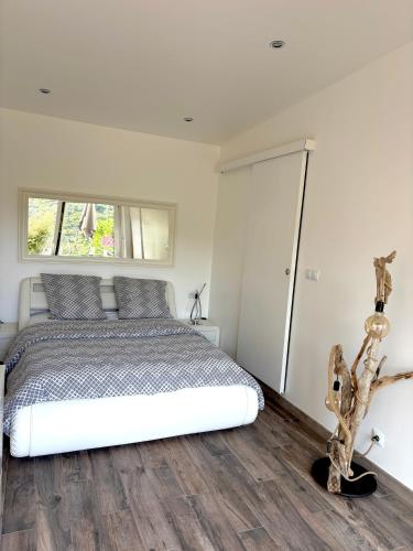 a bedroom with a white bed and wooden floors at Petit Havre de Paix avec Jacuzzi Luxe & Jardin Privatif Zen in Cavalaire-sur-Mer