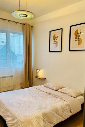 une chambre avec un lit et deux tableaux au mur dans l'établissement Le Cosy - Royal Park - Saint Brieuc, à Saint-Brieuc