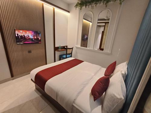 a bedroom with a bed and a mirror and a television at Hotel Ocean Residency Thane West in Thane