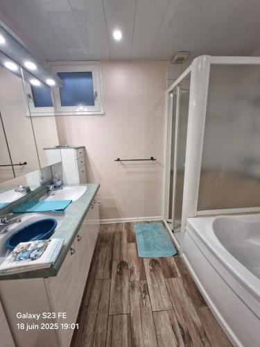 une salle de bain avec deux lavabos, une baignoire et une douche dans l'établissement Deux chambres confortables, à Morbier