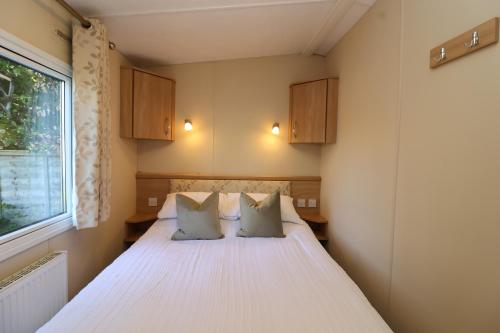 a bedroom with a bed with two pillows and a window at The Coop - Family Friendly caravan near Glastonbury & Street in Compton