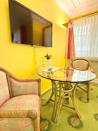 a dining room with a glass table and a flat screen tv at Boutique Hotel Villa am See in Hagnau