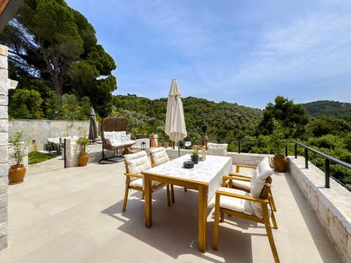 a patio with a table and chairs and a umbrella at Damari Luxury Retreat Villas Skiathos in Skiathos Town