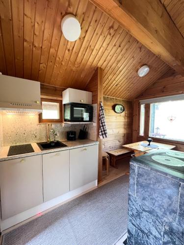 a kitchen with white cabinets and a wooden ceiling at Vuorijärvi cottage in Enonkoski