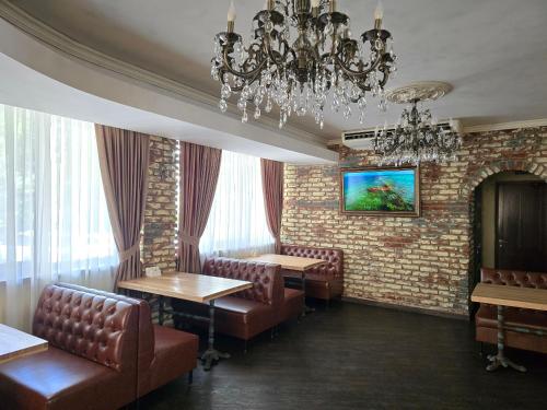 a restaurant with chairs and tables and a chandelier at Wellotel Chornomorsk in Chornomorsk