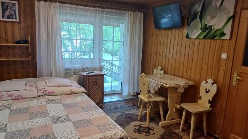 a bedroom with a bed and a desk and a window at Willa Irys in Bukowina Tatrzańska