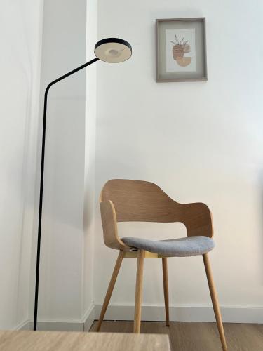 a chair sitting next to a floor lamp at Le Cocon des Tilleuls - Duplex 2 Ch - Parking inclus au pied du logement ! in Liège