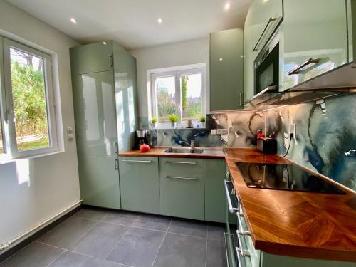 une cuisine avec des placards verts et un comptoir en bois dans l'établissement Magnifique Maison vue mer 150m de la plage, à Trouville-sur-Mer