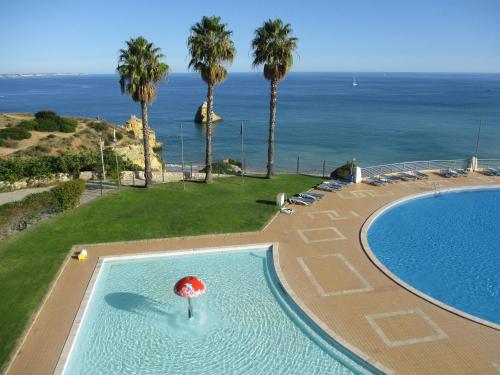 a swimming pool with a red umbrella and the ocean at Dona Ana Beach - Dream Flat in Lagos
