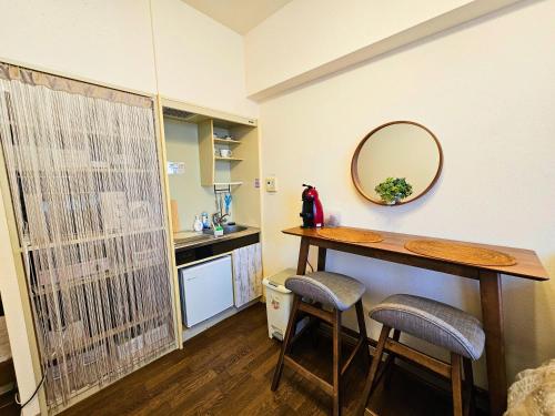 a kitchen with a table and two stools and a mirror at Cozy room Airport and Disneyland direct bus in Tokyo