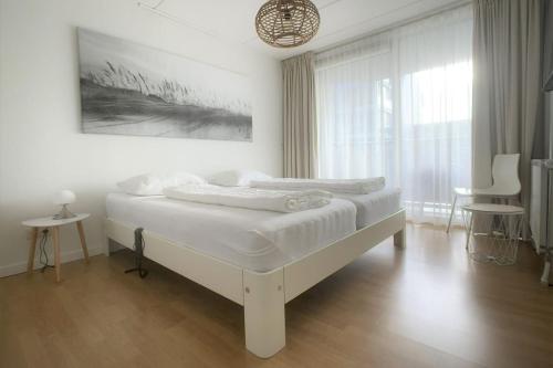 Un dormitorio blanco con una cama y una ventana grande. en Duinroosje, en Cadzand