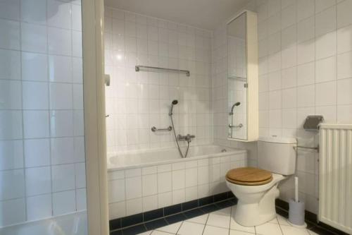 y baño con aseo y bañera con ducha. en Duinroosje, en Cadzand