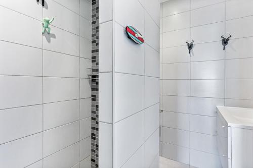 La salle de bains est pourvue de murs carrelés blancs et d'une douche. dans l'établissement appartement 1ère ligne face à la mer, à Palavas-les-Flots