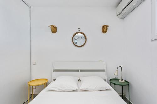 un lit blanc avec deux chaises et une horloge au mur dans l'établissement appartement 1ère ligne face à la mer, à Palavas-les-Flots