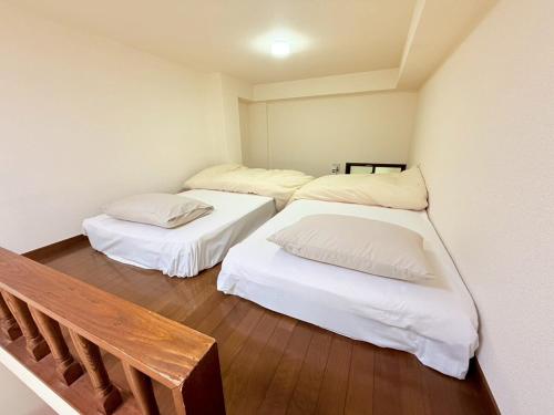 a room with three beds and a bench in it at 西山ハウス103 in Nagasaki