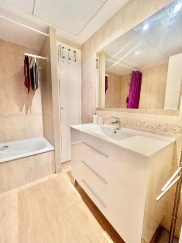 a white bathroom with a sink and a tub and a tubermott at Playa La Patacona in Valencia