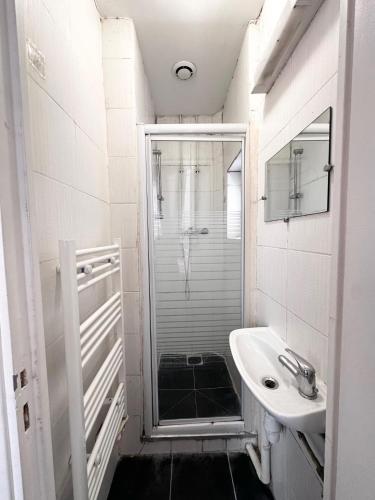 une salle de bain blanche avec une douche et un lavabo dans l'établissement Jojo appartement 1 chambres Paris-La défense, à Puteaux