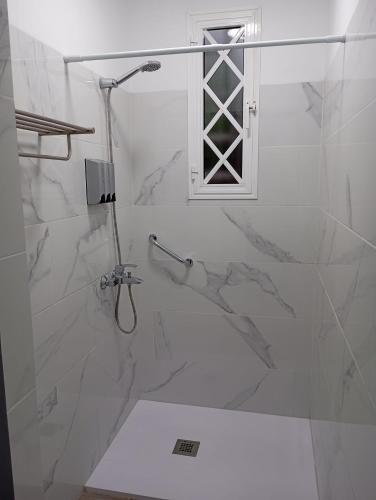 a white bathroom with a shower with a window at Guesthouse Los Geranios in Mocanal