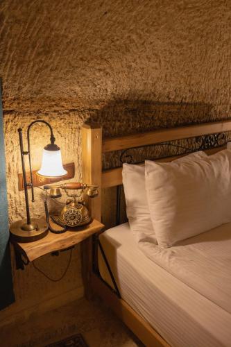 a bedroom with a bed with a lamp on a night stand at Peruna Cave in Goreme