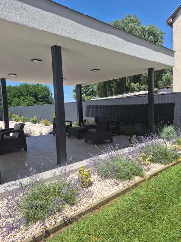 acovered patio with furniture and flowers on a roof at Kriszta Deluxe Vendégház in Újfehértó