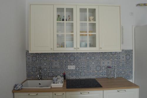 una cocina con armarios blancos y fregadero en Apartment Vela, en Neum