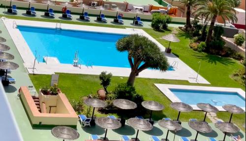 an overhead view of a swimming pool with umbrellas next to a resort at Hotel Pyr private studio in Fuengirola