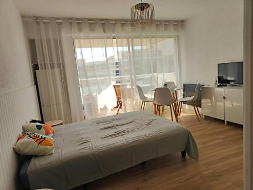 une chambre avec un lit, une table et des chaises dans l'établissement Studio entre mer et port a Carnon plage, à Mauguio