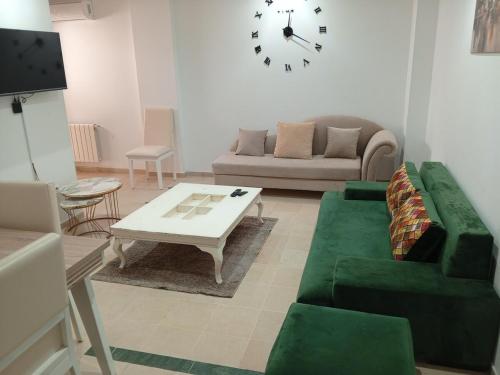 a living room with a couch and a table and a clock at Le bon sejour in El Aouina Station