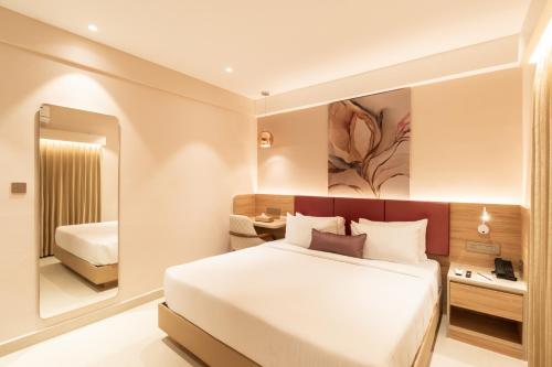 a bedroom with a large white bed and a mirror at TGI Livancia The Sojourn in Bengaluru