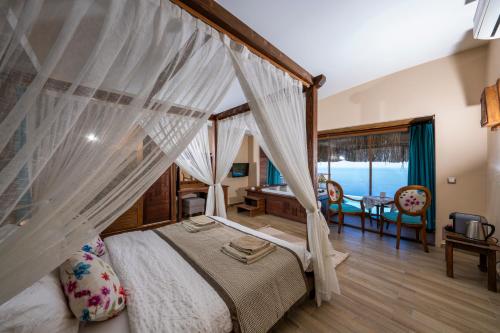 a bedroom with a canopy bed with a table and chairs at Lissiya Hotel in Faralya