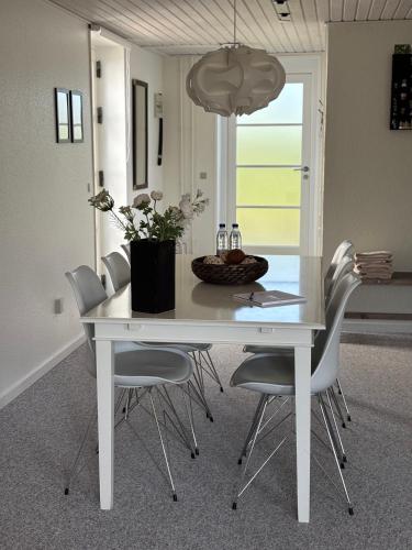 a white dining room table with chairs and a potted plant at Gæstehuset Rosenvang in Bogense